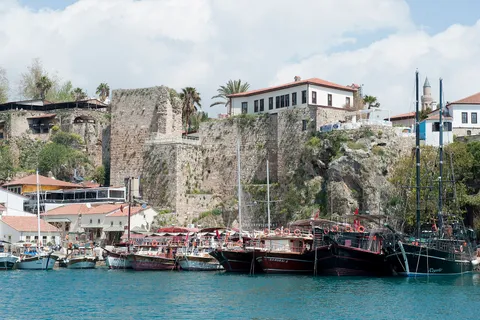 Boats moored in Antalya's old harbor beneath the historic Kaleiçi city walls