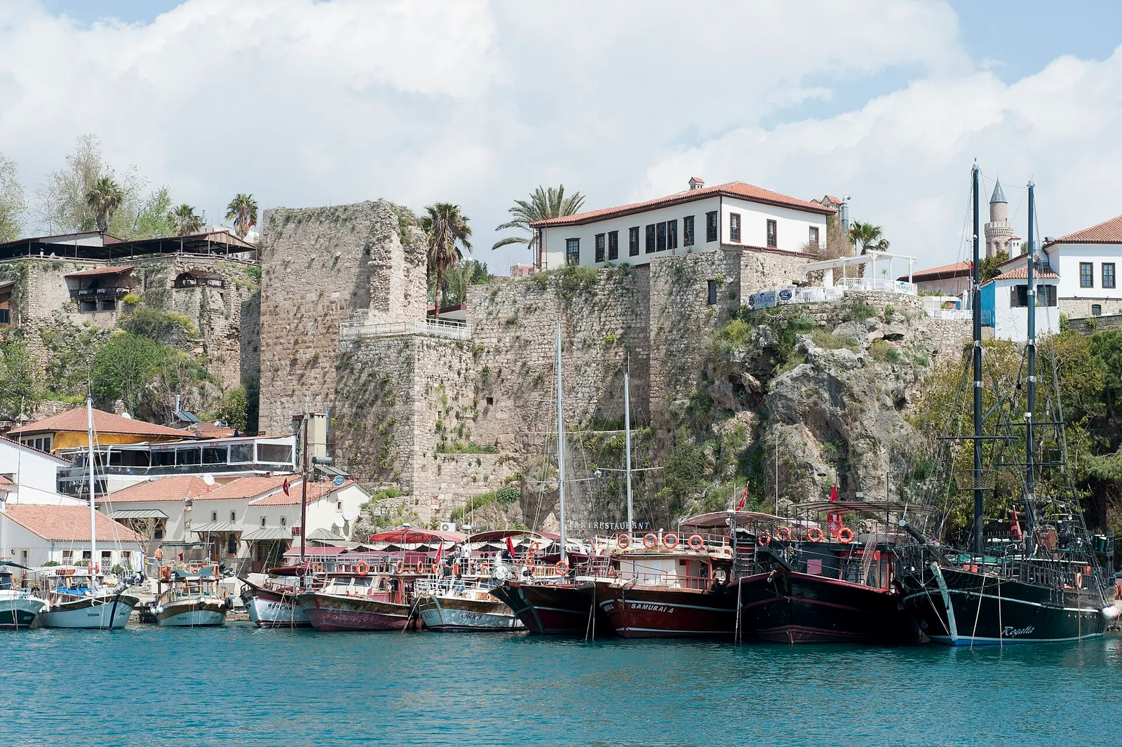 Boats moored in Antalya's old harbor beneath the historic Kaleiçi city walls
