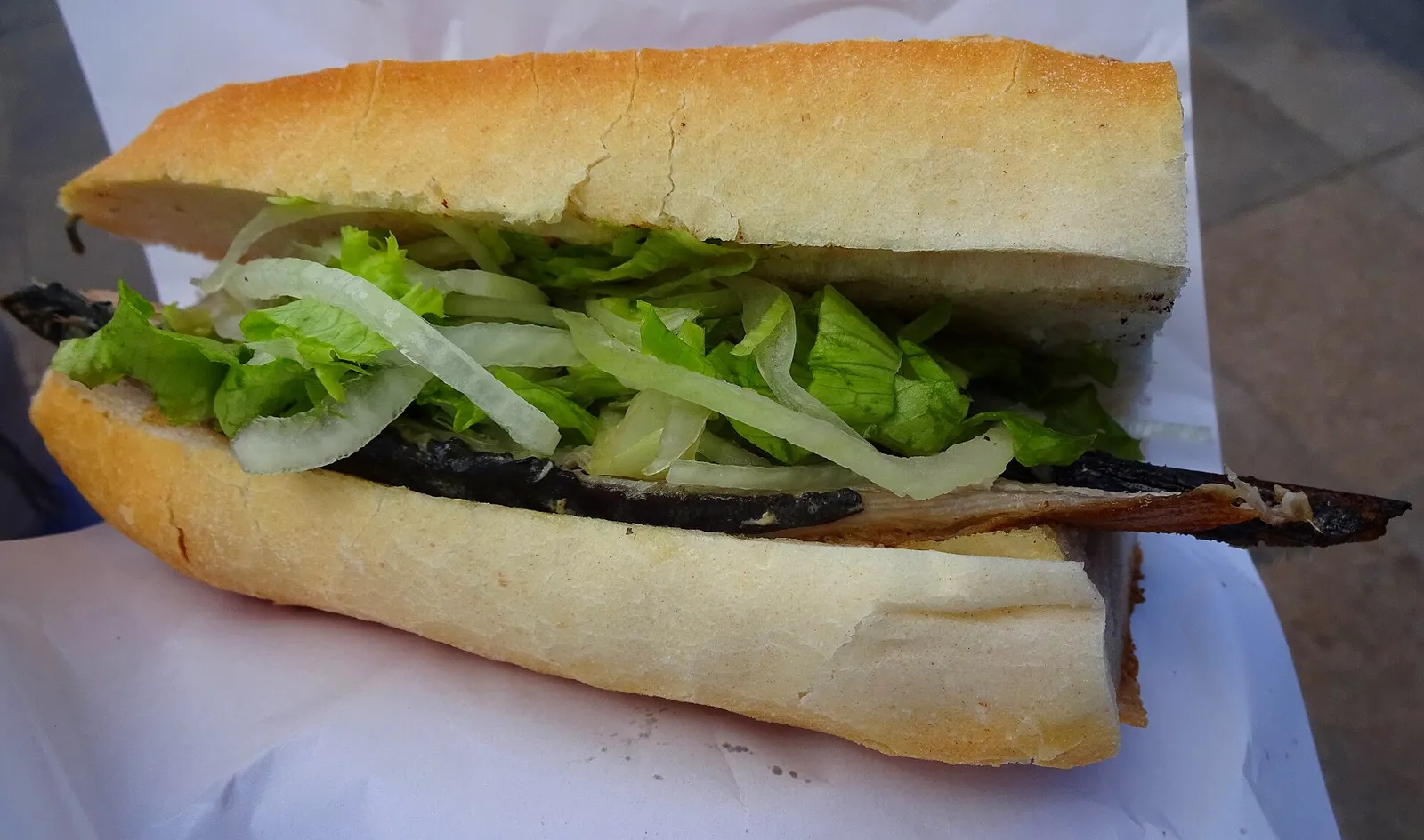 A grilled fish sandwich (balık ekmek) served from a vendor boat near Galata Bridge