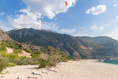 Aerial view of the turquoise Blue Lagoon beach at Ölüdeniz with a paraglider overhead